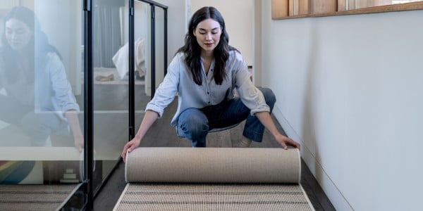 Woman unrolling rug runner upstairs